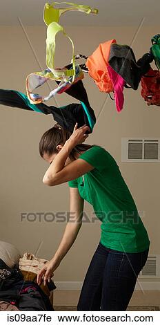 Stock Image - Mid adult woman anxiously looking for garment. Fotosearch