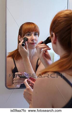 Mid adult woman applying blusher in mirror View Large Photo Image Picture - Mid adult woman applying blusher in mirror. Fotosearch