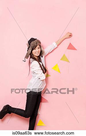 Mid adult woman holding bunting against pink background View Large Photo Image Stock Photograph - Mid adult woman holding bunting against pink background. Fotosearch