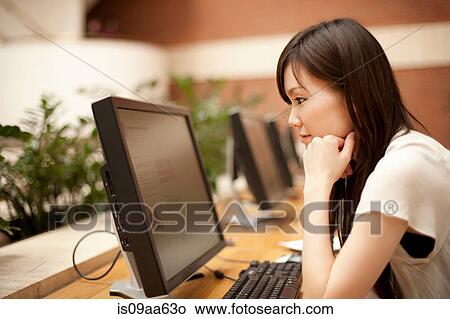 Picture - Mid adult woman looking at computer monitor. Fotosearch