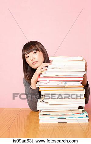Mid adult woman looking at stack of books on desk View Large Photo Image Stock Photograph - Mid adult woman looking at stack of books on desk. Fotosearch