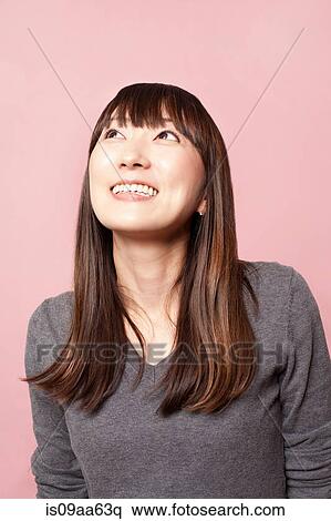 Mid adult woman smiling and looking up against pink background View Large Photo Image Stock Photography - Mid adult woman smiling and looking up against pink background. Fotosearch