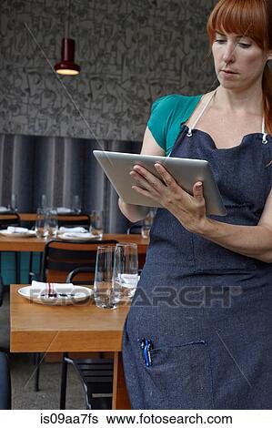 Mid adult woman using digital tablet in restaurant View Large Photo Image Stock Photograph - Mid adult woman using digital tablet in restaurant. Fotosearch