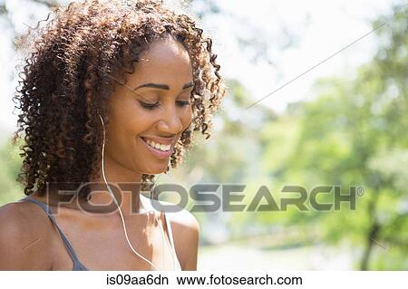 Mid adult woman wearing earphones, smiling View Large Photo Image Picture - Mid adult woman wearing earphones, smiling. Fotosearch