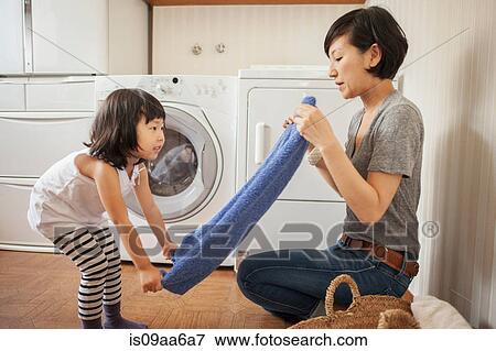 Stock Photo - Mother and daughter folding towel. Fotosearch