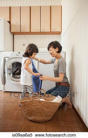 Stock Photography - Mother and daughter folding towel. Fotosearch