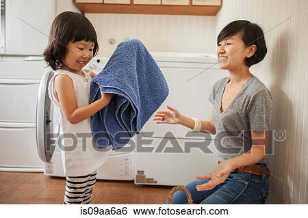 Stock Photograph - Mother and daughter, girl folding towel. Fotosearch