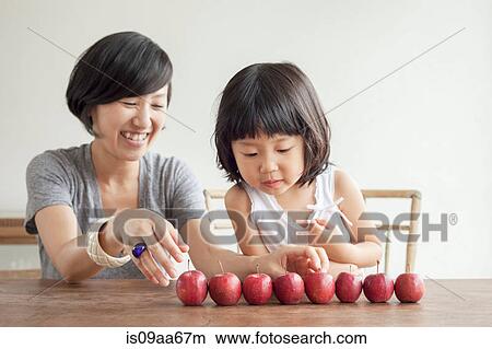 Picture - Mother and daughter with red apples in a row. Fotosearch