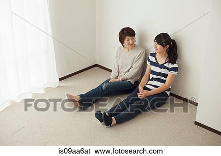 Stock Photograph - Mother and teenage daughter sitting on floor, portrait. Fotosearch
