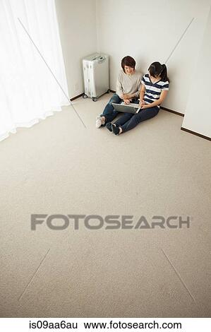 Mother and teenage daughter sitting on floor using laptop View Large Photo Image Stock Photograph - Mother and teenage daughter sitting on floor using laptop. Fotosearch