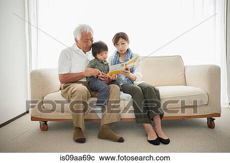 Stock Image - Mother reading to son sitting on grandfather's lap. Fotosearch