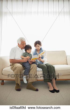 Stock Image - Mother reading to son sitting on grandfather's lap. Fotosearch