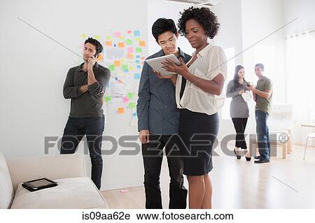 Stock Image - Office workers looking at digital tablet. Fotosearch