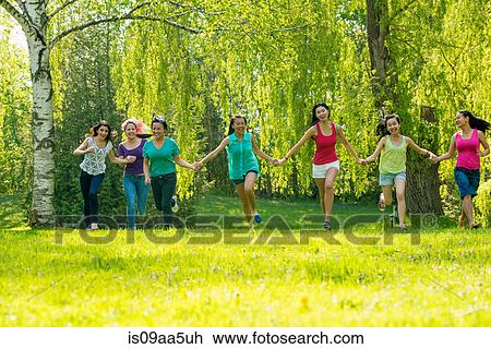 Stock Image - People running in park holding hands. Fotosearch