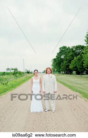 Portrait of couple on wedding day standing on dirt track View Large Photo Image Stock Image - Portrait of couple on wedding day standing on dirt track. Fotosearch