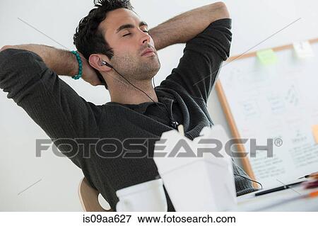 Stock Photo - Portrait of male listening to earphones. Fotosearch