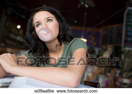 Stock Photo - Portrait of teenage girl blowing bubblegum in coffee house. Fotosearch