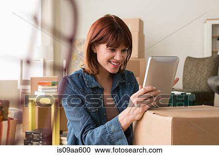 Portrait of woman holding digital tablet amongst cardboard boxes View Large Photo Image Stock Image - Portrait of woman holding digital tablet amongst cardboard boxes. Fotosearch