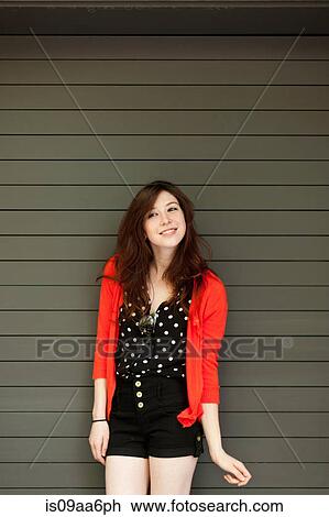 Stock Image - Portrait of young woman in front of shutter. Fotosearch