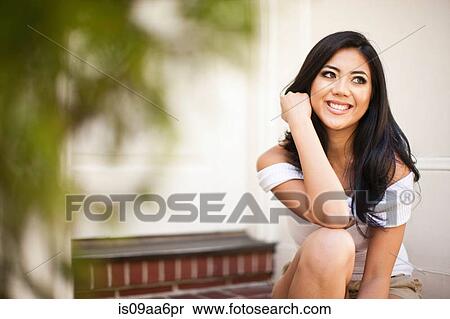 Stock Photography - Portrait of young woman on front door steps. Fotosearch