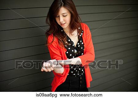 Stock Image - Portrait of young woman waiting on sidewalk. Fotosearch