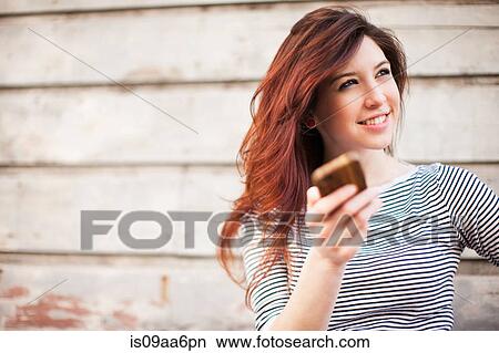 Picture - Portrait of young woman with smartphone. Fotosearch