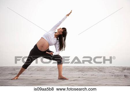 Stock Photo - Pregnant woman in yoga lunging pose. Fotosearch