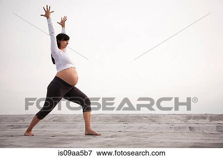 Stock Photo - Pregnant woman in yoga warrior pose. Fotosearch