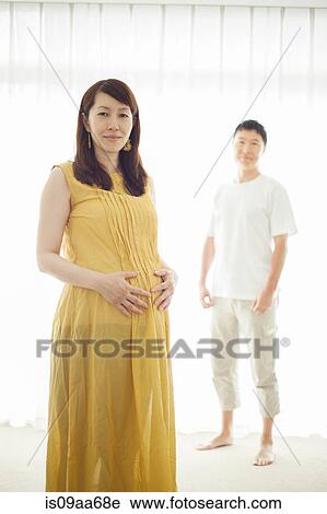 Stock Image - Pregnant woman with man in background, portrait. Fotosearch