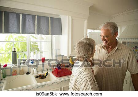 Stock Image - Senior couple in kitchen, smiling. Fotosearch