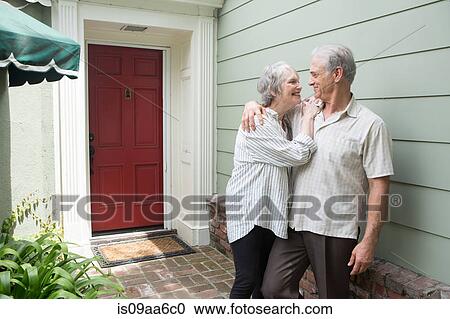 Stock Image - Senior couple smiling together outside house. Fotosearch