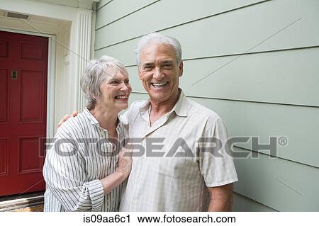 Stock Image - Senior couple smiling together outside house, portrait. Fotosearch