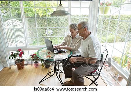 Senior couple using laptop in conservatory View Large Photo Image Picture - Senior couple using laptop in conservatory. Fotosearch