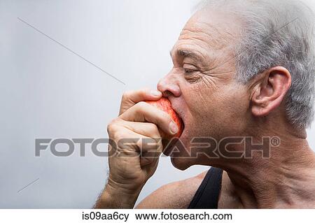 Stock Photo - Senior man eating apple, close up. Fotosearch
