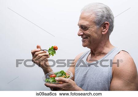 Stock Photograph - Senior man holding bowl of salad. Fotosearch