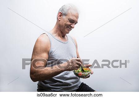 Stock Photography - Senior man holding bowl of salad. Fotosearch