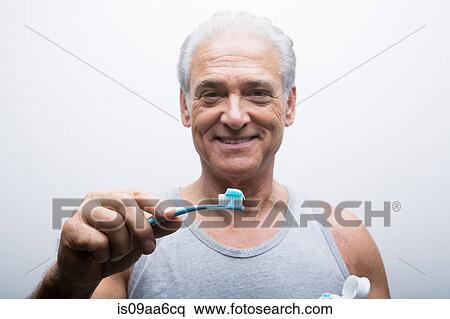 Stock Photography - Senior man holding toothbrush, portrait. Fotosearch
