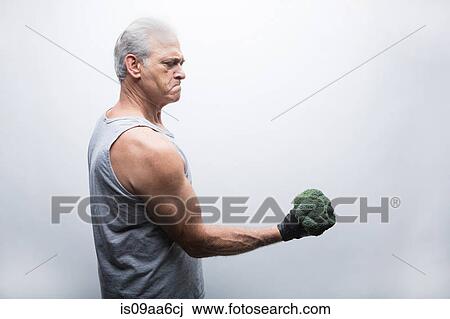 Senior man in sports clothing lifting broccoli View Large Photo Image Stock Image - Senior man in sports clothing lifting broccoli. Fotosearch