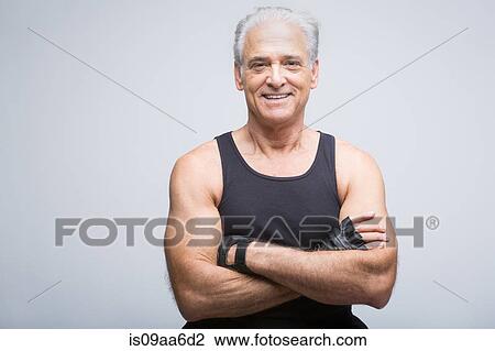 Stock Image - Senior man in sports clothing with arms crossed, portrait. Fotosearch