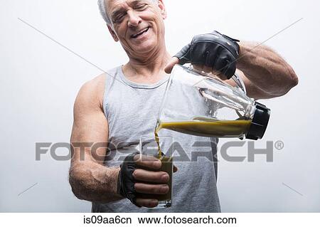 Picture - Senior man pouring smoothie from blender into glass. Fotosearch