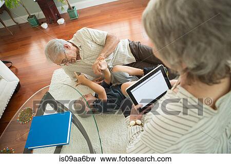 Stock Photo - Senior man tickling grandson on rug. Fotosearch
