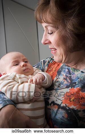 Stock Image - Senior woman holding baby boy, smiling. Fotosearch