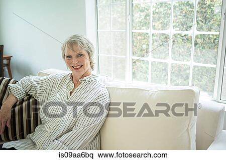 Stock Photography - Senior woman on sofa, portrait. Fotosearch