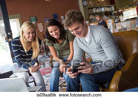 Stock Image - Small group of people looking at smartphone in cafe. Fotosearch