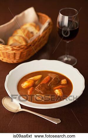 Stock Photograph - Still life of casserole in bowl with red wine and bread. Fotosearch