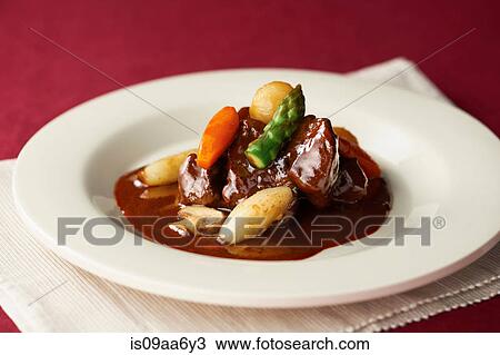 Stock Image - Still life of stew garnished with asparagus and carrot. Fotosearch