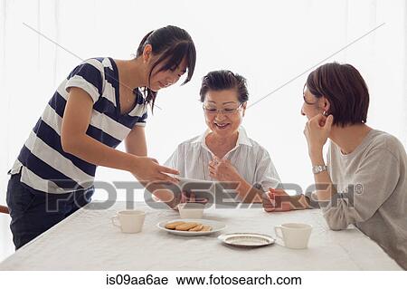 Stock Image - Teenage girl showing tablet to mother and grandmother. Fotosearch