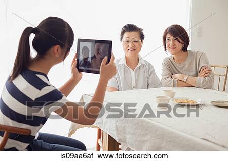 Teenage girl using tablet to photograph mother and grandmother View Large Photo Image Stock Image - Teenage girl using tablet to photograph mother and grandmother. Fotosearch