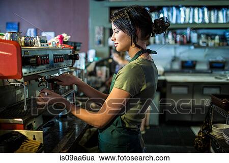 Stock Image - Teenage waitress preparing coffee in cafe kitchen. Fotosearch