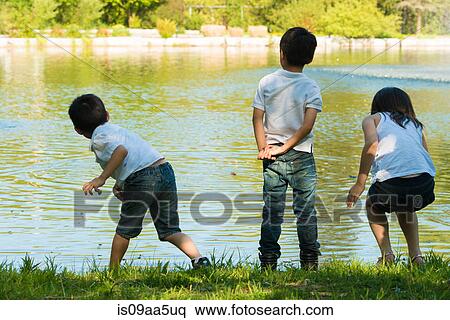Stock Photography - Three children playing by lake. Fotosearch